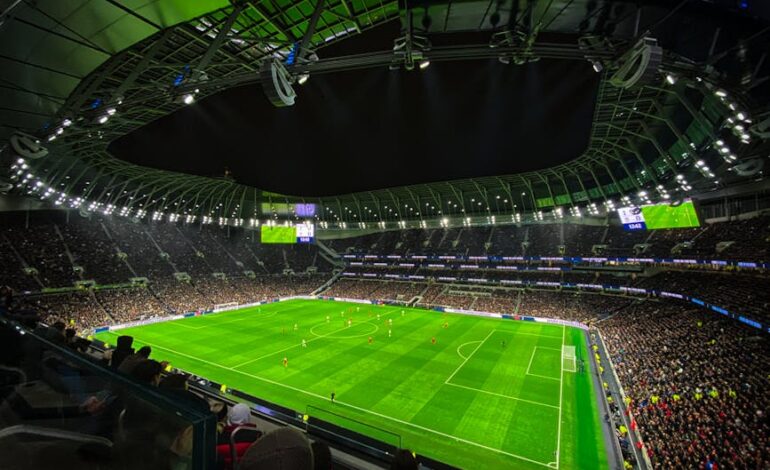 A captivating night football match at a packed stadium in England, showcasing dynamic gameplay and vibrant atmosphere.