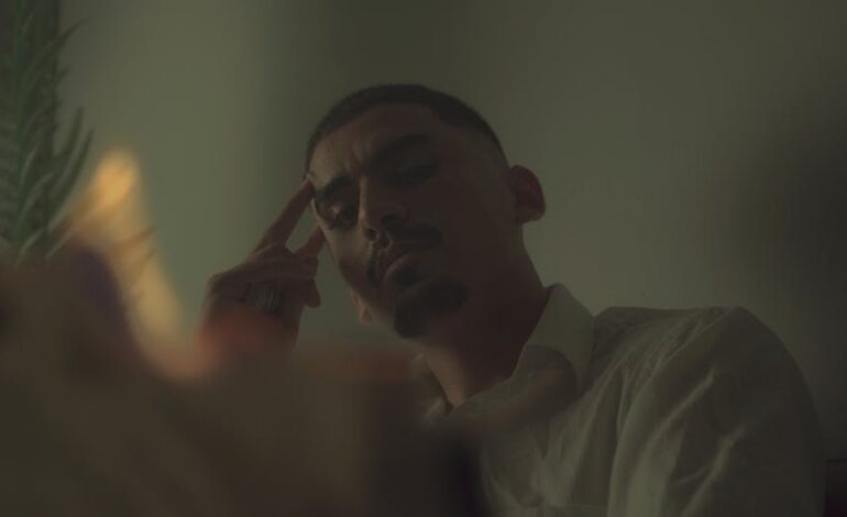 A contemplative man indoors with dramatic, moody lighting and a cinematic feel.