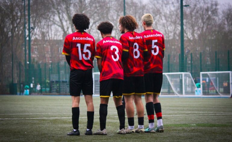 Four soccer players in red jerseys stand on the field, preparing for the game.