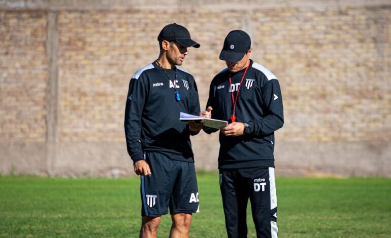 Two soccer coaches reviewing strategies on the field during the day.