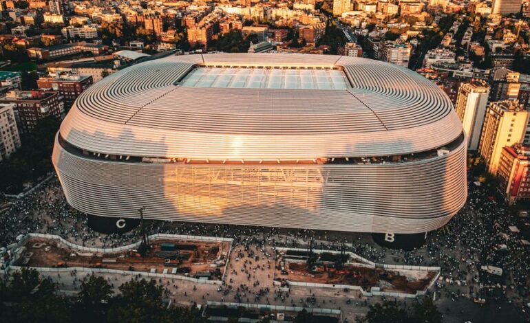 Stunning aerial shot of the Santiago Bernabéu Stadium, Madrid during sunset with bustling cityscape.
