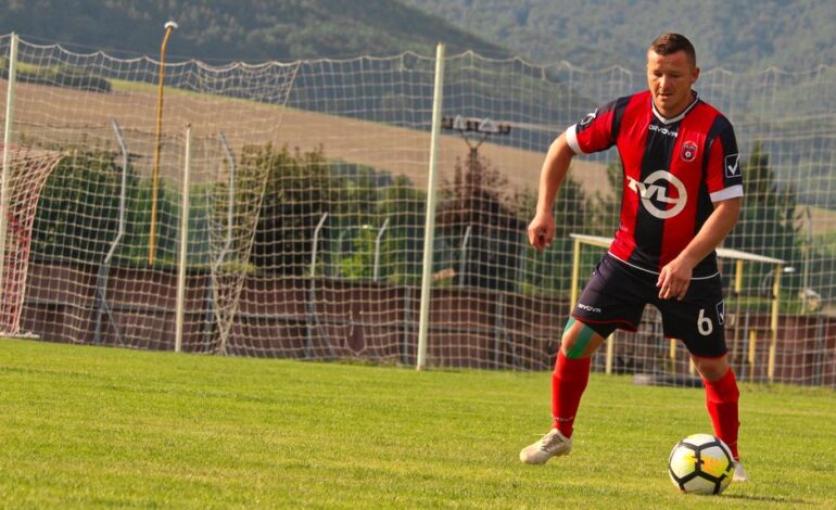 A soccer player in action on a sunny day at a field in Rajec, Slovakia.