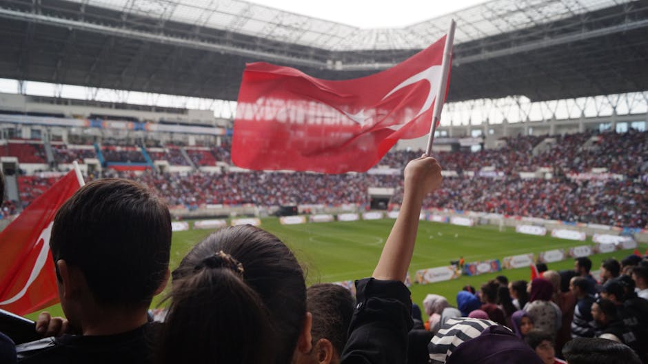 Crowd waving Turkish flags in a stadium during a lively football game.
