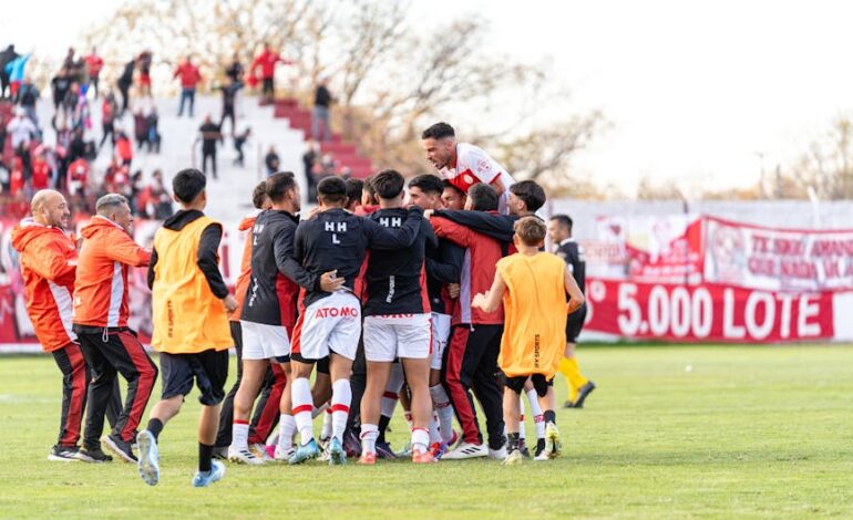 A team of joyful footballers celebrates a winning moment on the outdoor field.