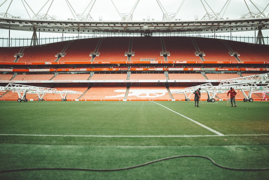 A view of Emirates Stadium in London, featuring the field and maintenance crew.
