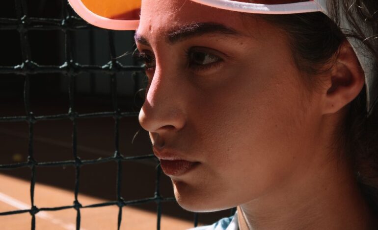 Close-up of a female tennis player in deep focus on the court next to the net.