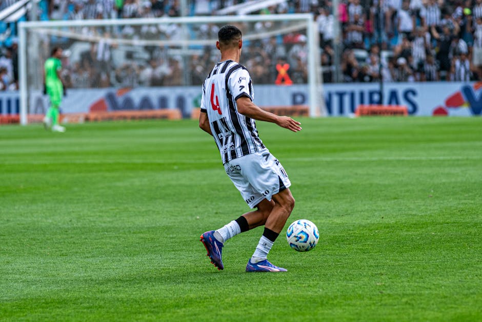 Soccer player dribbling the ball during a match on a sunny day.