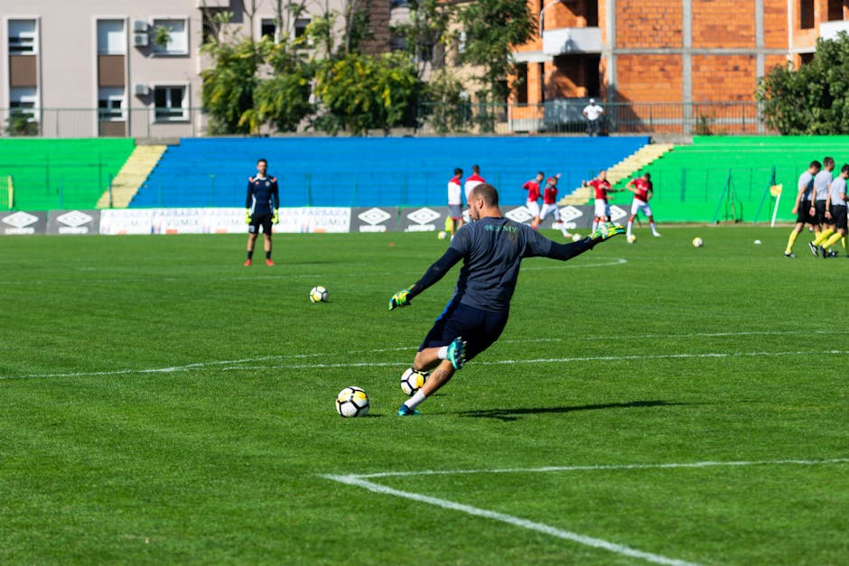 Soccer player in action during practice on a sunny day, kicking the ball on a green field.